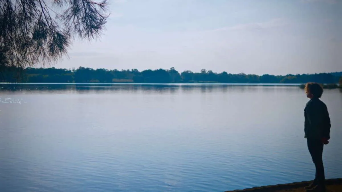 Persona contemplando un lago en calma al atardecer, símbolo de interioridad